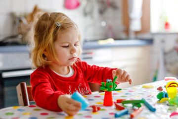Adorable cute little toddler girl with colorful clay. Healthy baby playing and creating toys from...