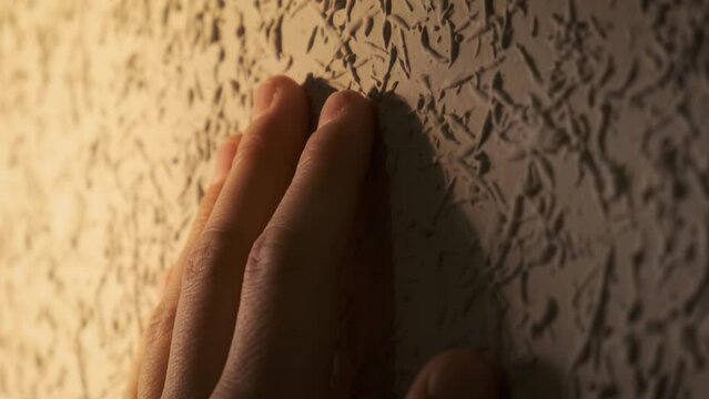 Male hand touching a convex wall with a decorative convex surface, close-up