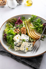 Healthy Salad made from Green Salad Leaves, Rocket Salad, Slices of Fresh Pears, pieces of Blue Cheese, Walnuts and Sesame Seeds.