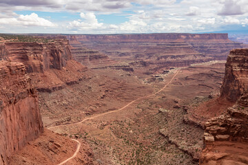Fototapeta na wymiar Scenic view from Shafer Trail Viewpoint in Canyonlands National Park near Moab, Utah, USA. Shafer Basin and La Sal Mountains in Colorado Plateau in distance. Off road trails leading down the canyon