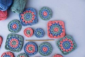Layout of granny squares and circles, a hook and skeins of yarn