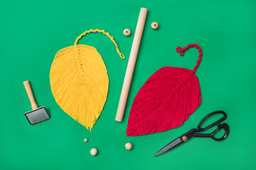 Macrame leaves, red and yellow, on green background with scissor