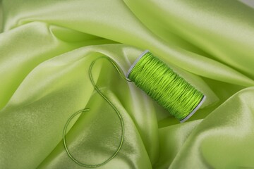 Green yarn cone on green soft fabric background