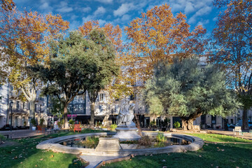 Nimes city, in France, a pretty wooded square in the historic centre, typical buildings
