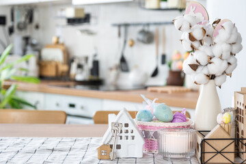 Key to house of cozy home with Easter decor with rabbit and eggs on table of kitchen. Building, design, project, moving to new house, mortgage, insurance, rent and purchase real estate