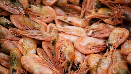 Pink fresh frozen shrimps with ice in a supermarket or fish shop. Uncooked seafood close up background. Fresh frozen prawns, delicacies, sea food concept, close up.