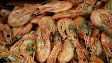 Pink fresh frozen shrimps with ice in a supermarket or fish shop. Uncooked seafood close up background. Fresh frozen prawns, delicacies, sea food concept, close up.