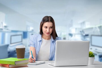 Happy female student sitting at the desk with laptop