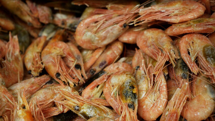 Pink fresh frozen shrimps with ice in a supermarket or fish shop. Uncooked seafood close up background. Fresh frozen prawns, delicacies, sea food concept, close up.