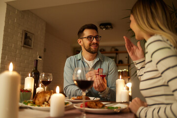 Fototapeta na wymiar Delighted woman looking at her boyfriend while getting a marriage proposal over romantic dinner at home