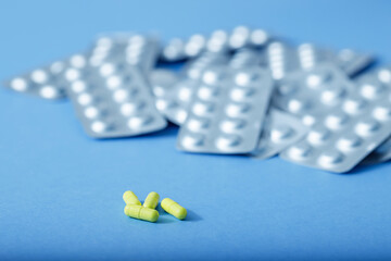 Yellow capsules and different blister of pills. Different pills. Medical and different concept of light blue paper background with copy space.