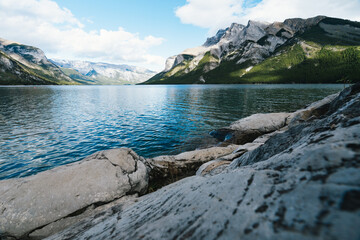 Obraz premium Lake Minnewanka in Alberta, Canada on a cloudy day with stunning mountains and water reflections