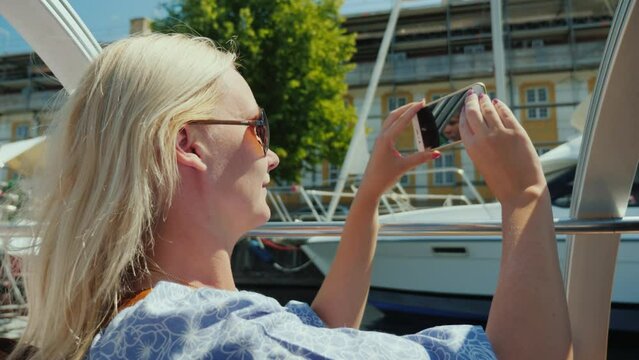A woman takes pictures of Copenhagen's city line, sails on a sightseeing boat