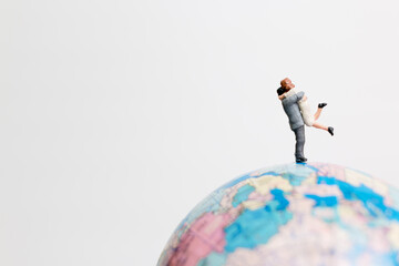 Miniature people figure standing on the globe world map