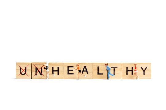 Miniature people running on wooden letter block on white background