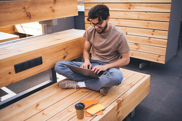 Focused young man using laptop on wooden bench