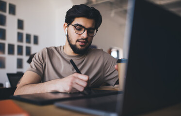 Focused young man writing on tablet