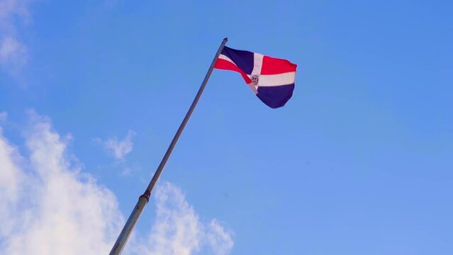 Dominican Republic Flag flapping in wind under blue sky