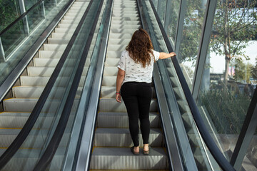 Woman with a white blouse in a mall going on upstairs