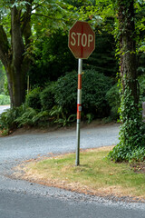 Stop sign on corner with green trees and bushes