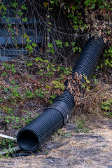 Large black drainage pipe emerging from hillside