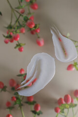 a smear of white cream of a thick consistency on a transparent surface with a background of red hypericum flowers