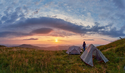 Tent camp of tourists against the backdrop of a stunning dawn. Beautiful morning, the girl enjoys the amazing mountain view