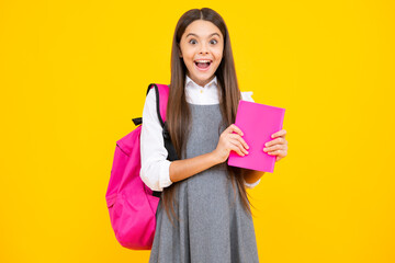 Schoolgirl, teenage student girl hold book on yellow isolated studio background. School and...