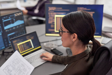 Side view portrait of woman as female IT engineer working with data at desk