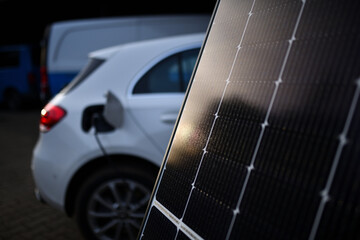 Solarmodul vor Hybrid Elektroauto beim Aufgeladen an der Tankstellen Steckdose. Solar Tanken mit...