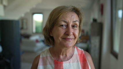 Portrait of a happy senior woman standing indoors at home. Close up face of a mature female person...