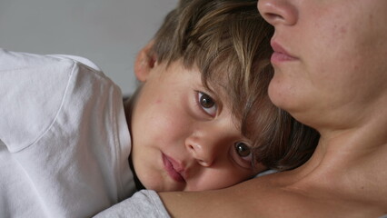 One thoughtful little boy leaning on mother chest. Pensive child close up face lying on parent body. Contemplative small boy resting with mom