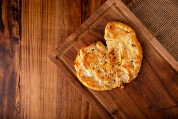 Homemade roasted chicken breast, flattened and seasoned on rustic wooden table. Closeup image.