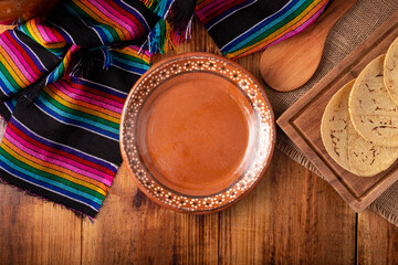 Cooking background with empty mud dish, mexican typical fabric on rustic wooden table. Table top...
