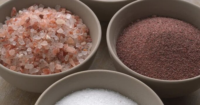 Assortment of salt types: pink Himalayan, black (kala namak), sea salt, rock salt. Table spin.