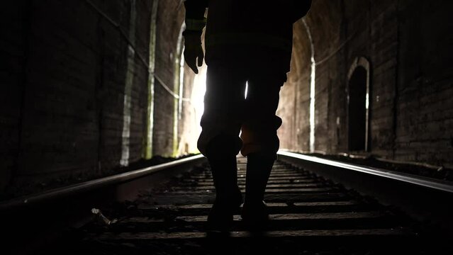 a railway engineer worker with a lantern in his hands walks through the tunnel