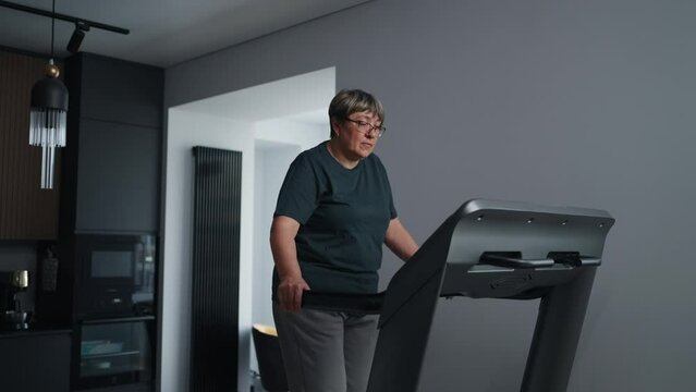 Elderly Woman Training Alone At Home, Walking On Treadmill, Cardio Workout For Good Health
