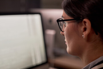 Closeup of serious businesswoman using computer while working at night in office, copy space