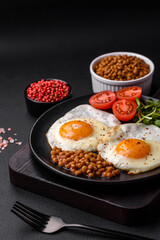 Delicious hearty breakfast consisting of two fried eggs, canned lentils and microgreens