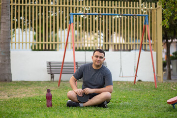 Man with a dumbbells in a park and a  bottle of water