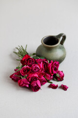 A bouquet of withered roses and a ceramic jug, a symbol of lost love.