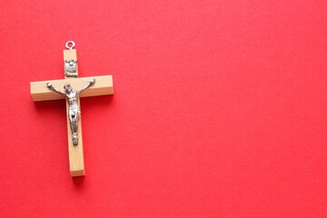 Crucifix christian wooden cross on red background with copy space. Catholic symbol. Flatlay, top...