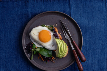Breakfast with toasted bread, sliced avocado, and fried egg, directly above
