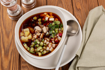 Sliced vegetables and meat for okroshka are laid out in a plate
