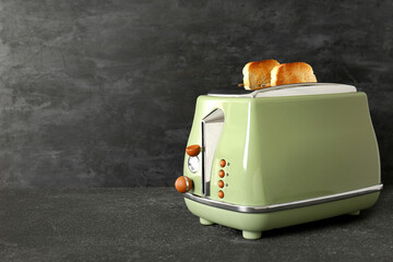 Modern toaster with crispy bread slices on black table