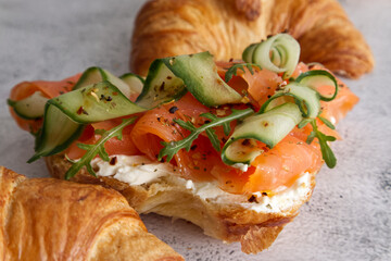 Croissants with cheese cream, red fish and cucumber close up 