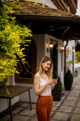 Young woman standing in the backyard and using mobile phone