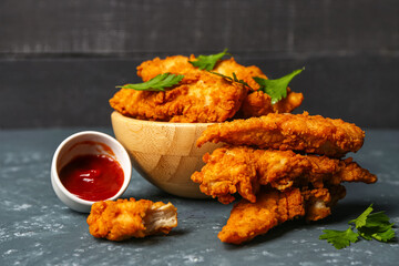 Bowl of tasty nuggets and sauce on dark table