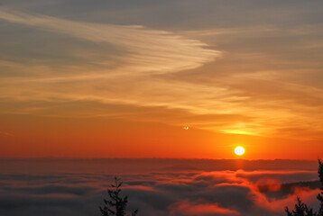 Orange and golden sunrise over a fog filled valley at the south end of Vancouver Island, BC