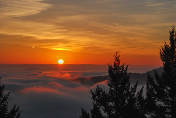 Orange and golden sunrise over a fog filled valley at the south end of Vancouver Island, BC